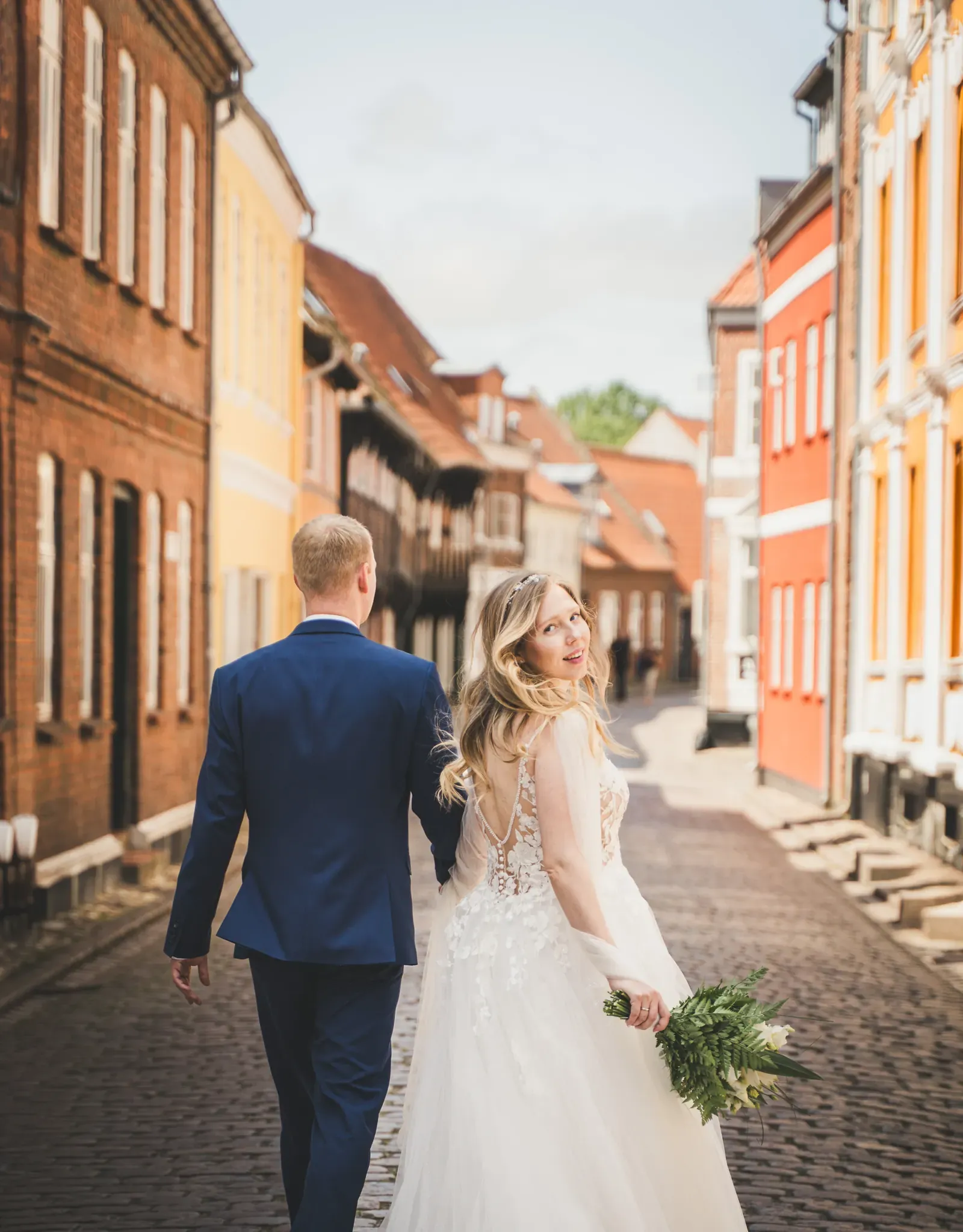 Bride and groom walking down a cobblestone lane in Ribe, Denmark